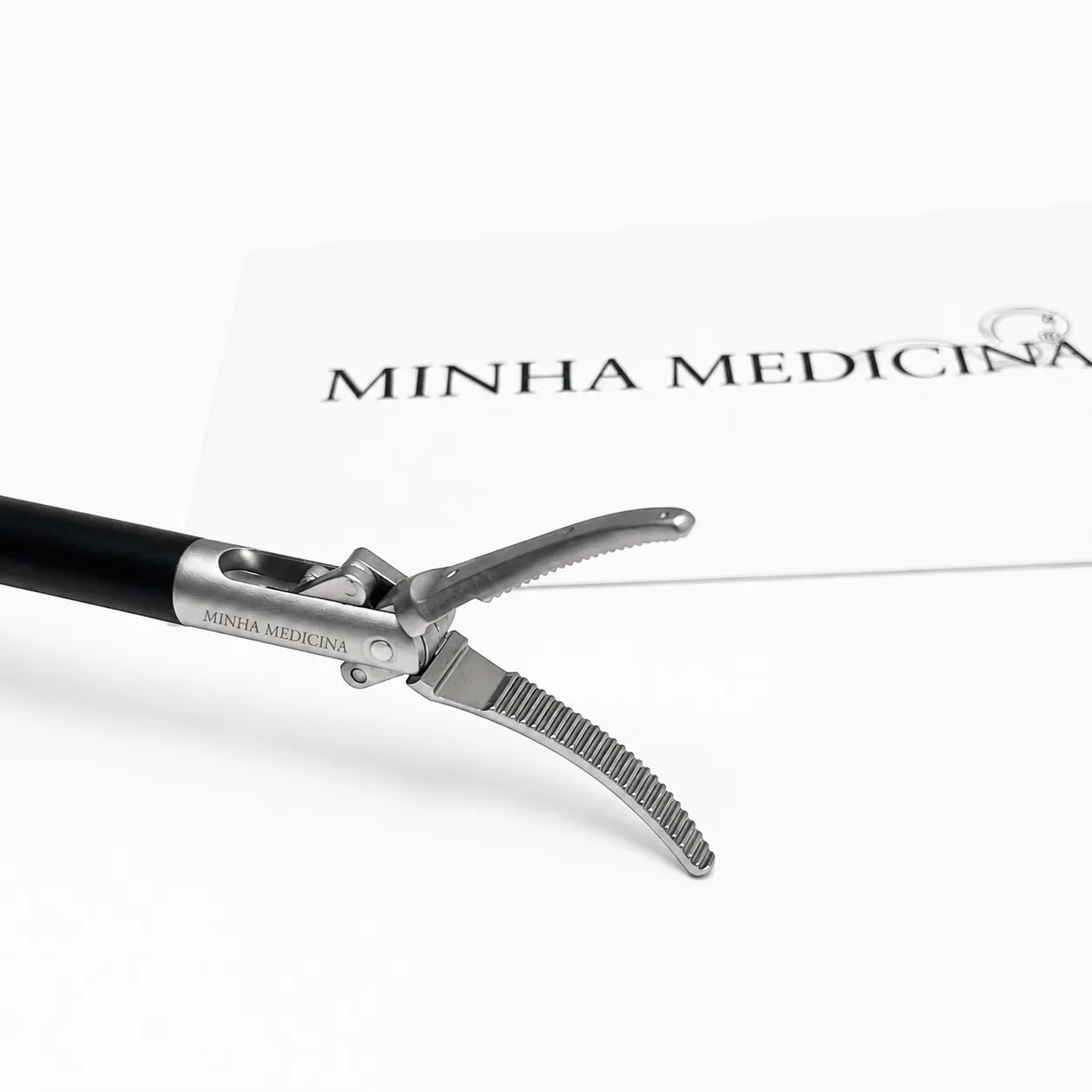 Pinça Maryland Dissecção 5mm: Pinça Maryland, ponta curva aberta sobre cartão Minha Medicina